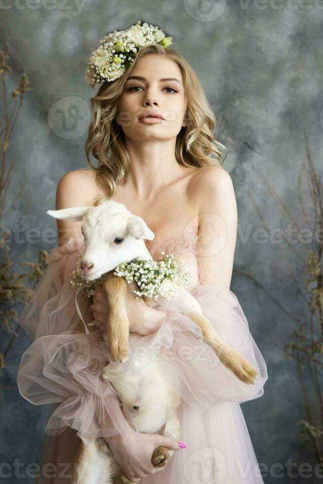 une Jeune blond femme dans un aéré rose robe avec une blanc enfant. printemps portrait de une femme. photo