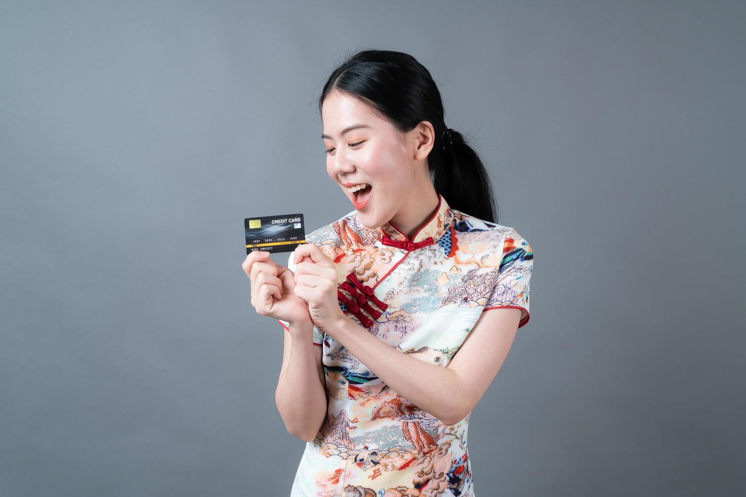 une femme asiatique porte une robe traditionnelle chinoise et tient une carte de crédit photo