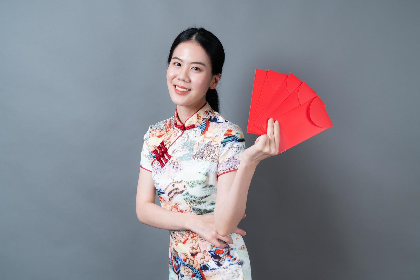 une femme asiatique porte une robe traditionnelle chinoise avec un paquet rouge photo