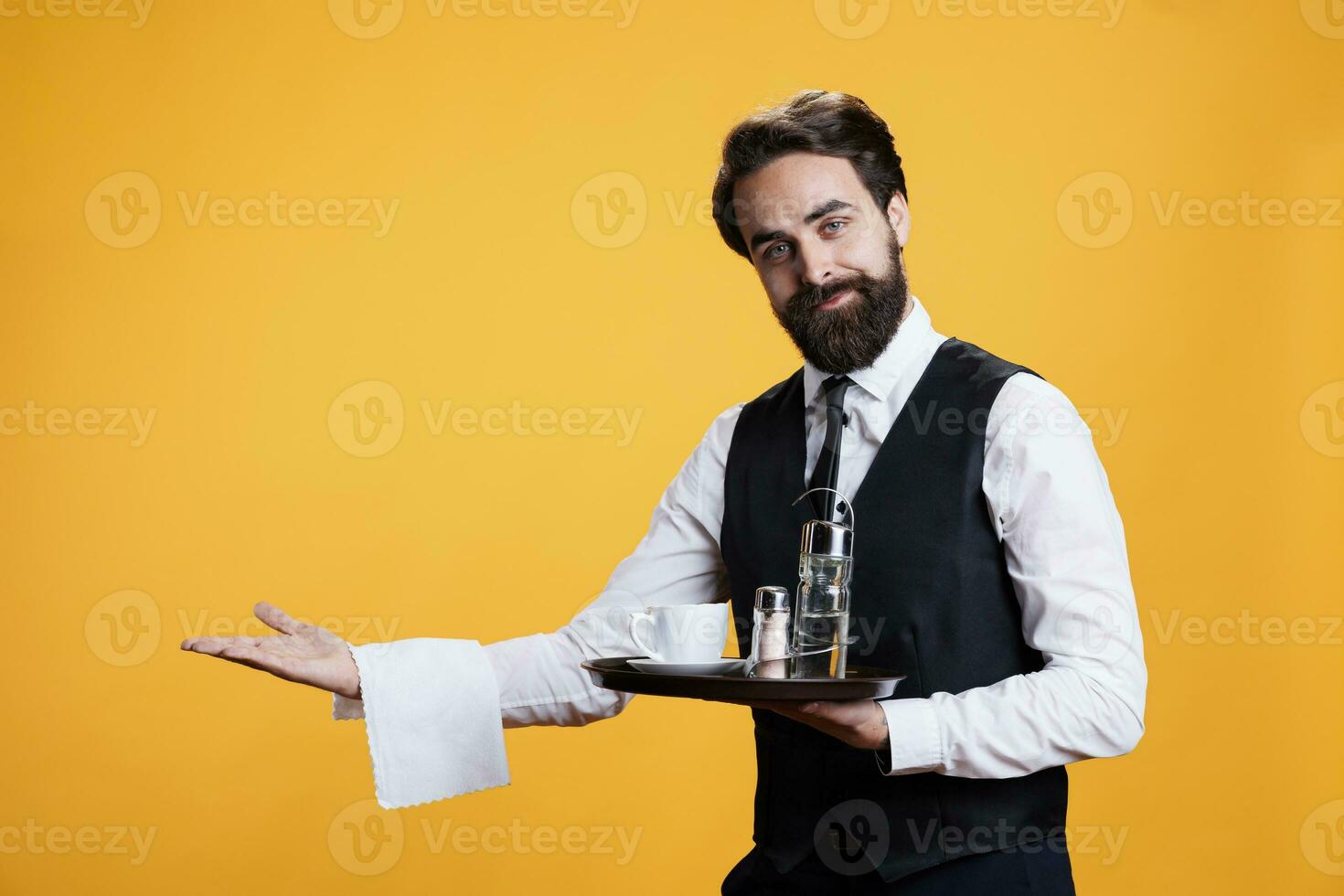 qualifié serveur spectacles direction à table à restaurant, portion gens comme profession. Jeune homme travail comme majordome avec repas plateau dans main, fait semblant à servir tasse de café à les clients sur caméra. photo