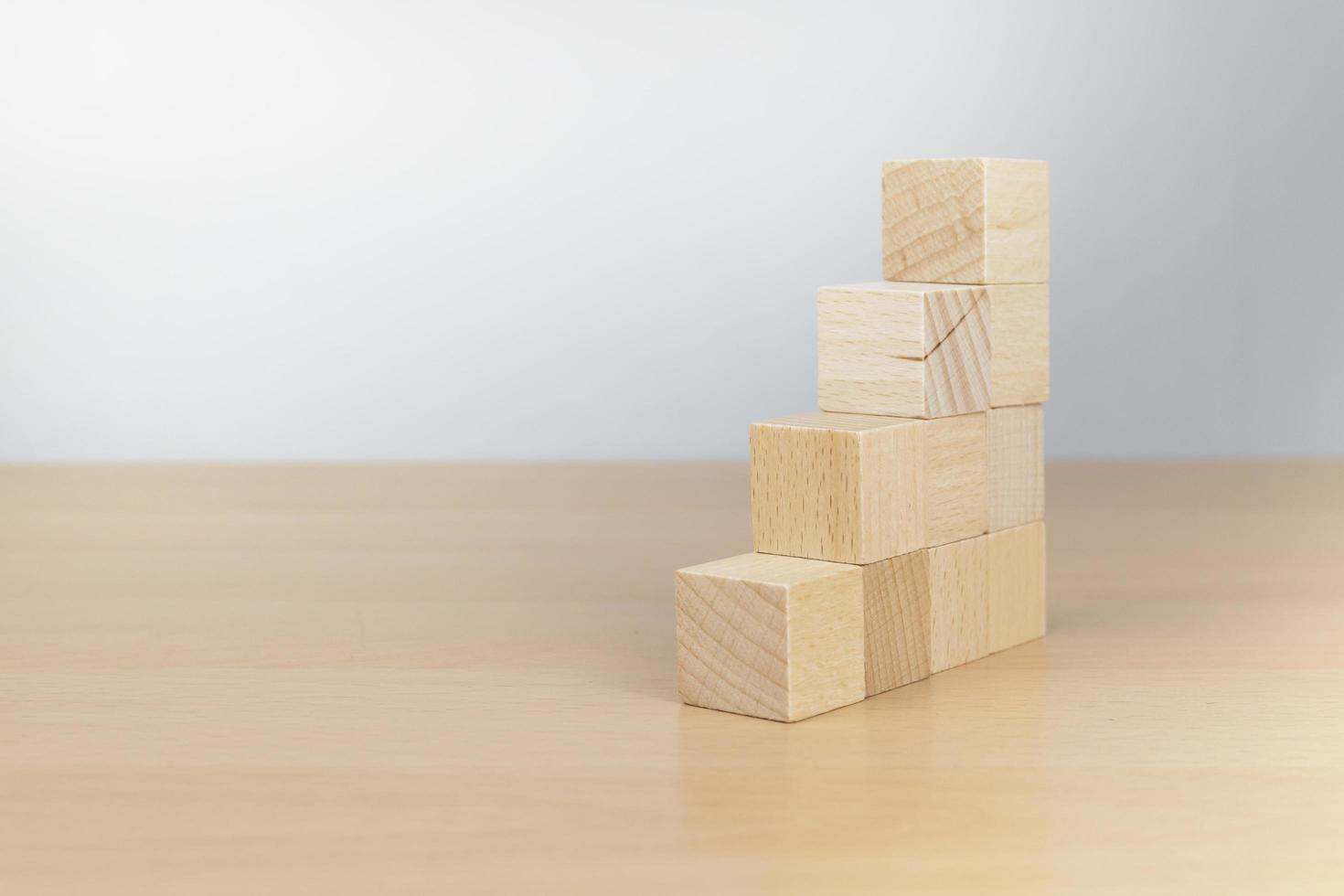 main organisant l'empilement de blocs de bois comme marche d'escalier sur une table en bois photo