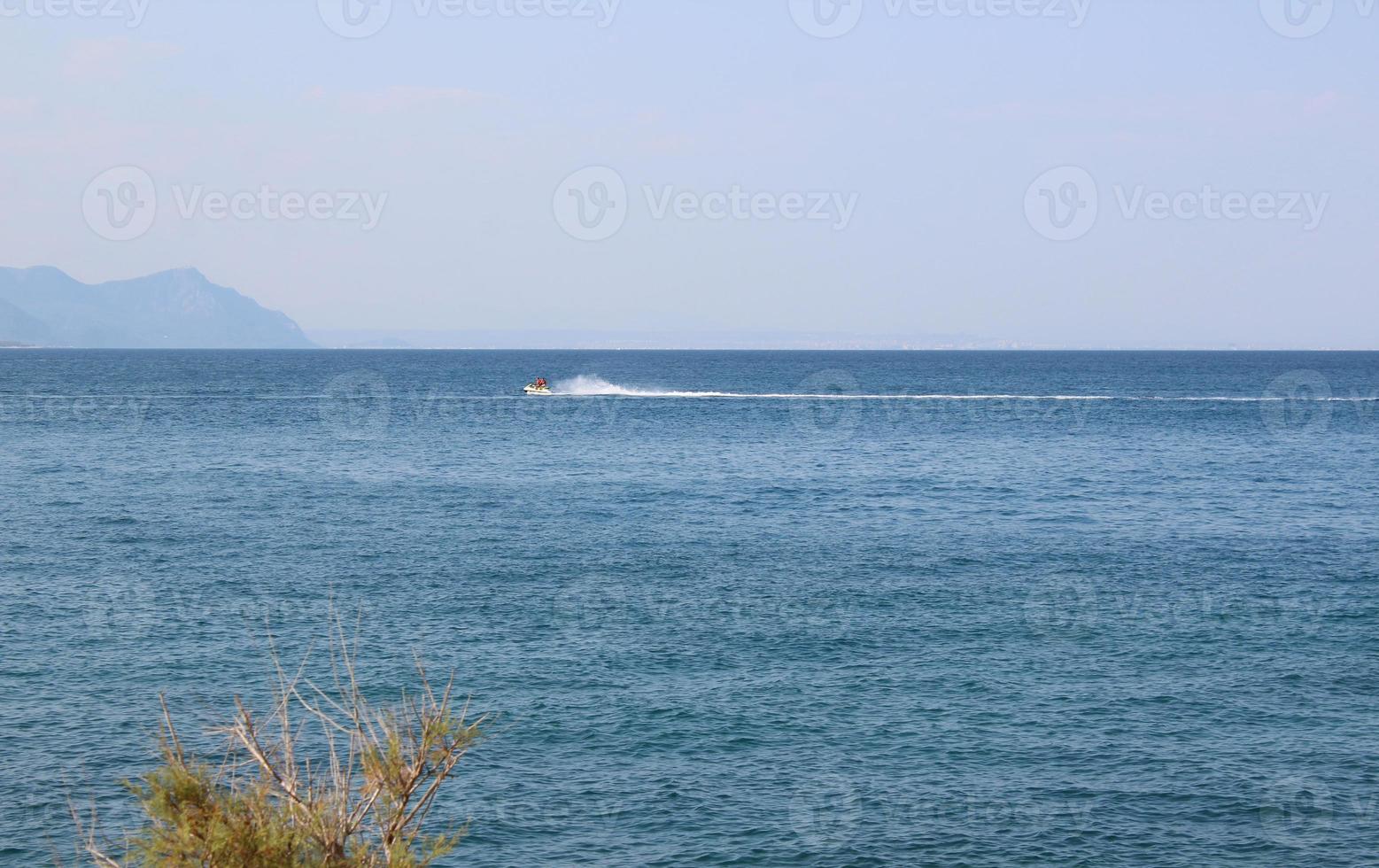 paysage marin avec des montagnes et des gens sur un jet ski photo