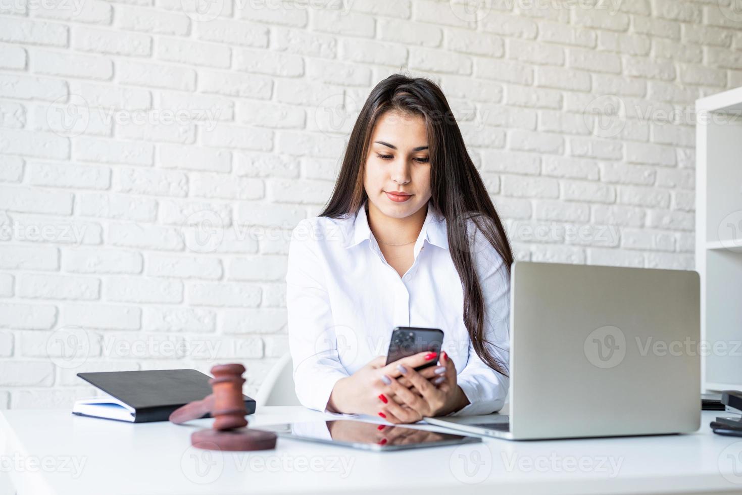 portrait d'une jeune avocate sur son lieu de travail à l'aide de son téléphone photo