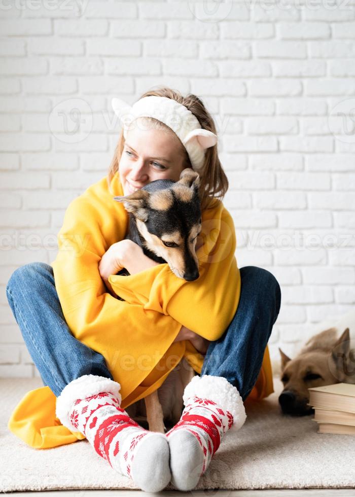 Funny young woman in plaid jaune assis sur le sol serrant son chien photo