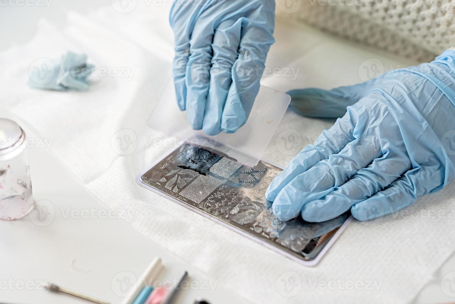 maître de manucure en masque et gants faisant tamponner au client photo