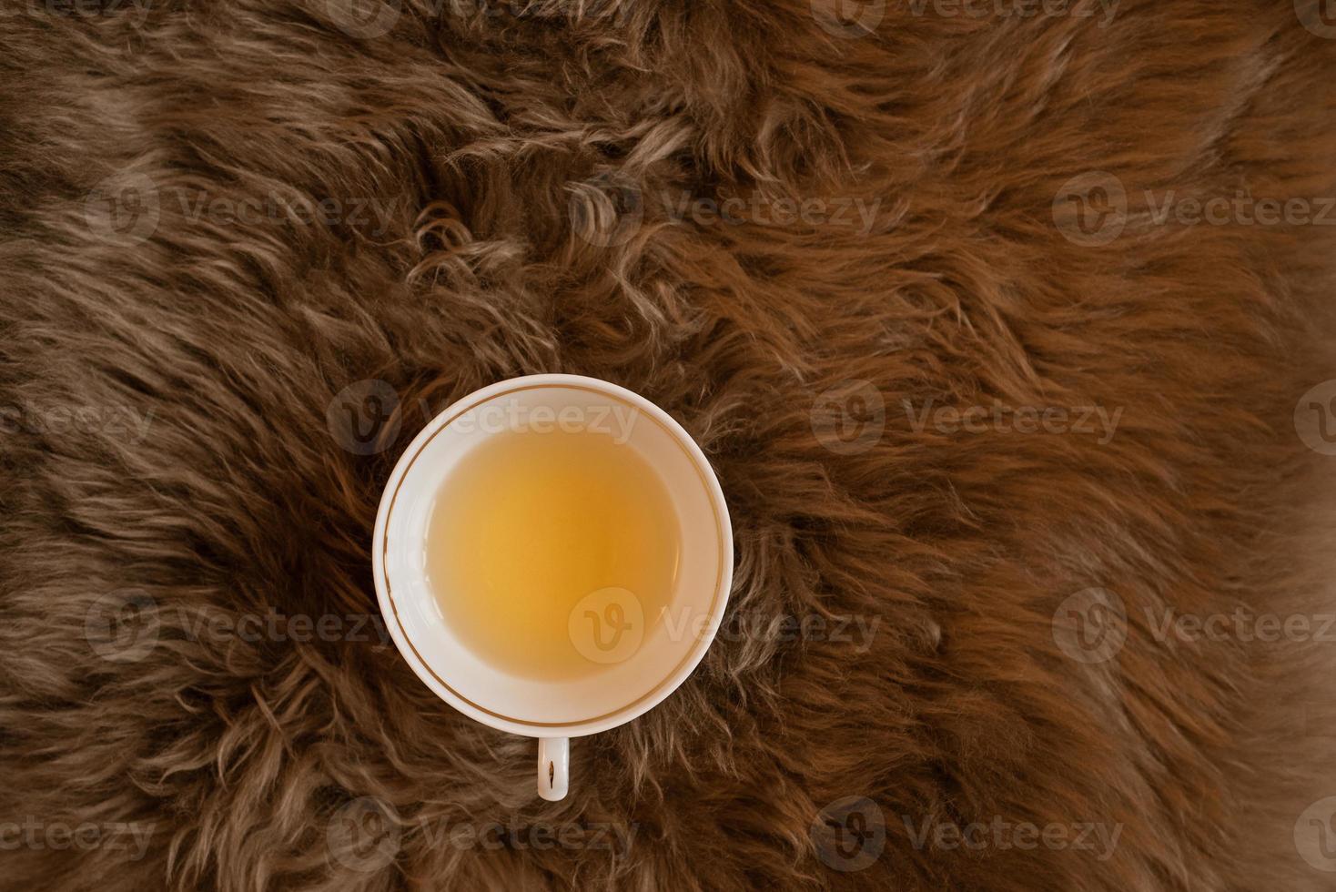 une tasse de thé vert sur le plaid en fourrure marron moelleux. photo
