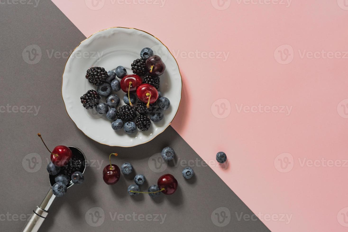 myrtilles, mûres, cerises sur assiette et cuillère à crème glacée photo