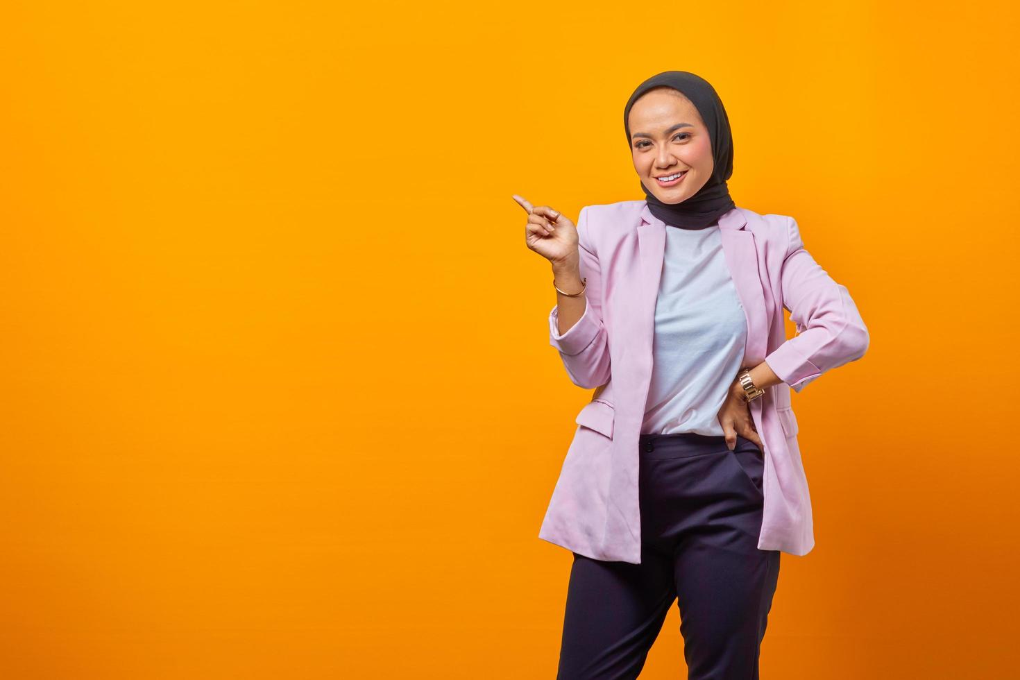 joyeuse femme asiatique attirante pointant le doigt sur un espace vide photo