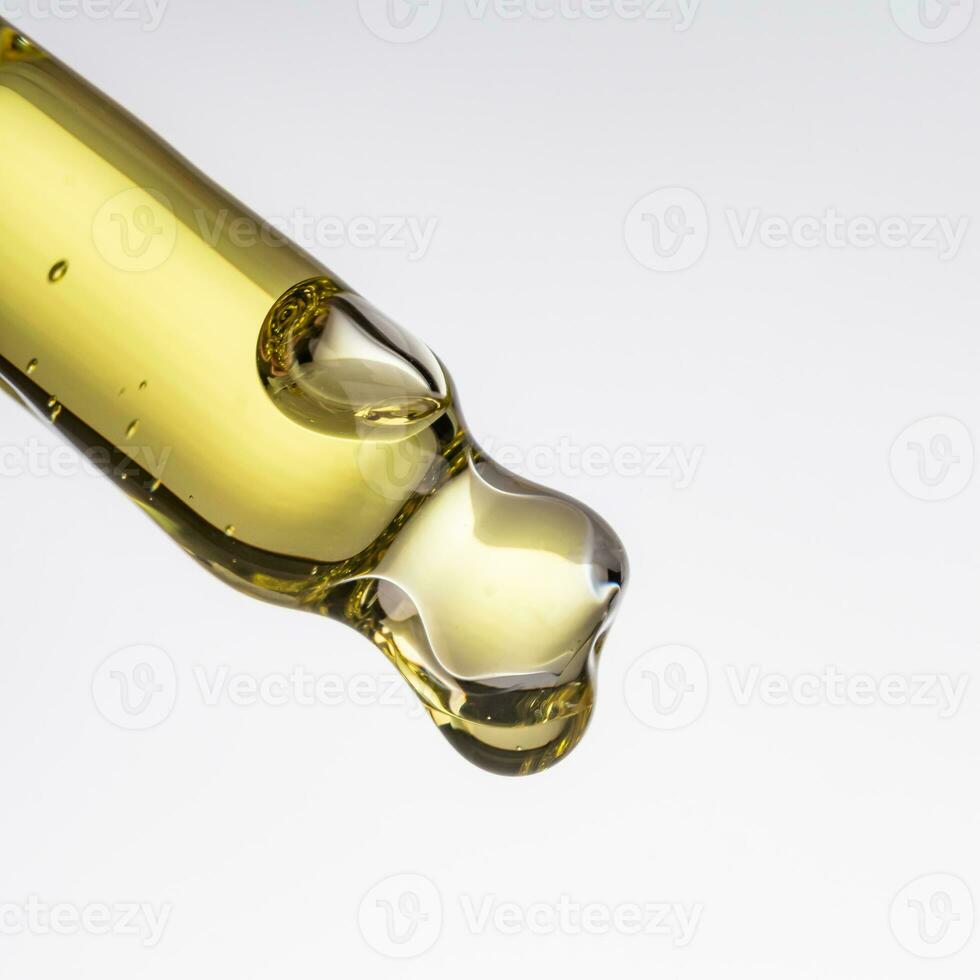Jaune essentiel sérum pétrole égouttage de or compte-gouttes isolé sur blanc Contexte. photo