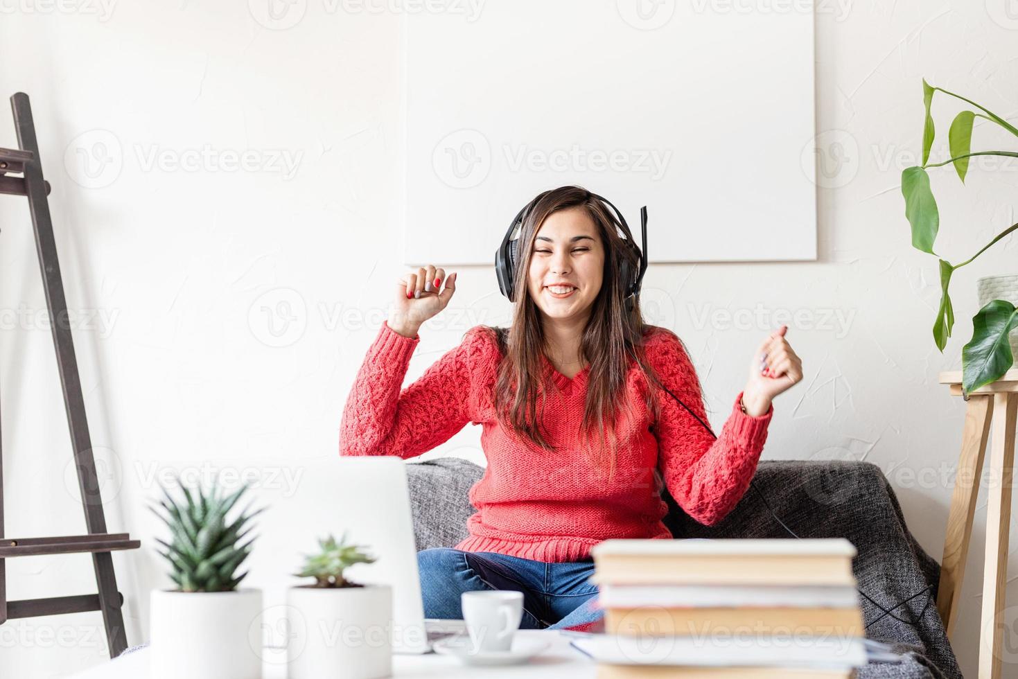 femme en pull rouge et casque noir assis sur le canapé dansant photo