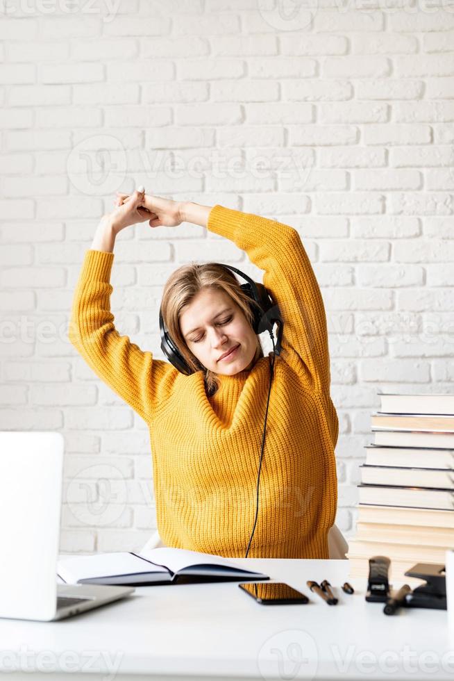 femme assise au bureau s'étirant après une longue étude photo