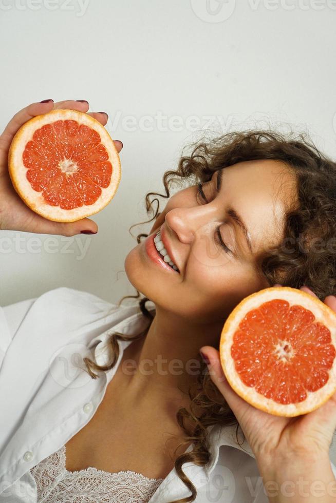 Portrait de jolie femme d'âge moyen aux cheveux bouclés avec pamplemousse photo