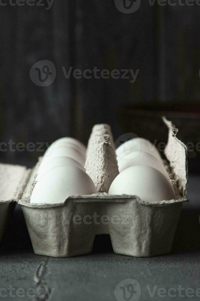 blanc des œufs dans une papier carton boîte sur une béton Contexte contre une en bois mur. en bonne santé biologique nourriture et agriculture concept photo