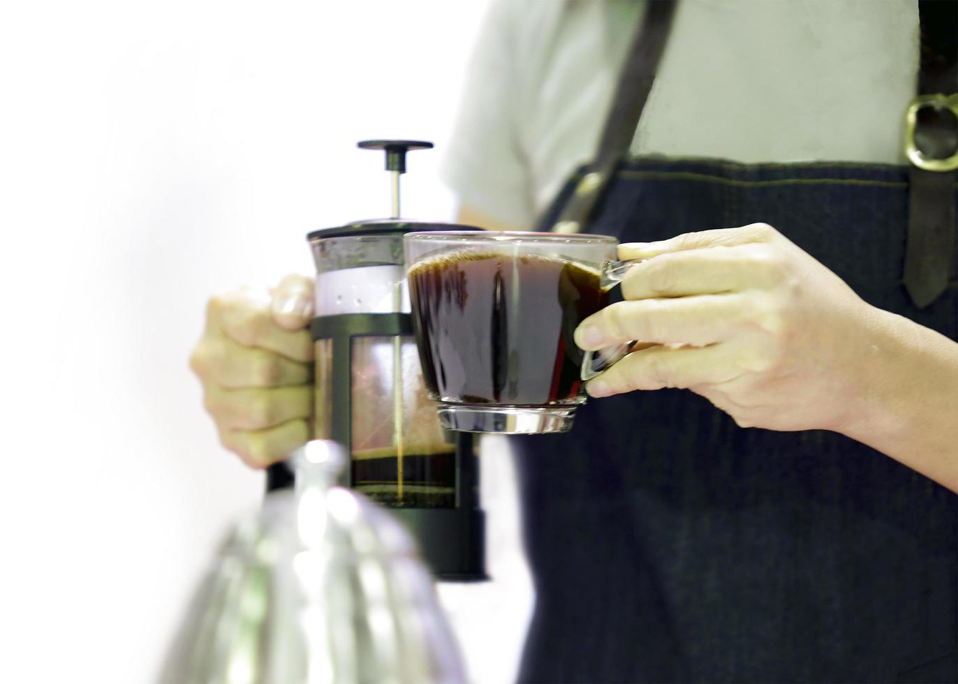 le barista verse le café d'une presse française dans la tasse photo