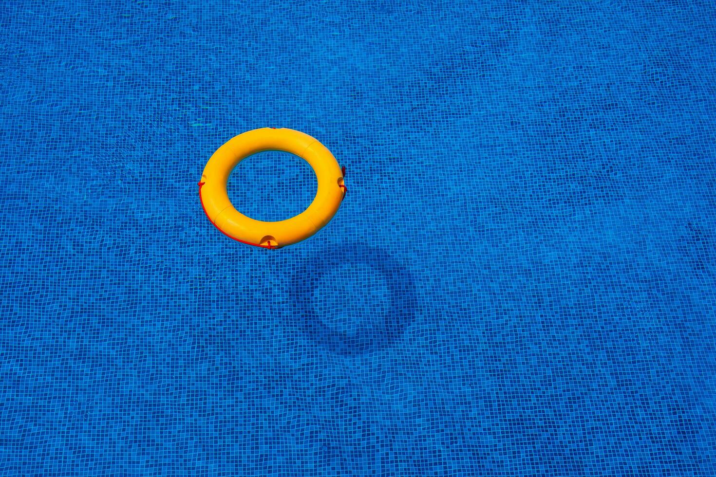 Haut vue de bouée de sauvetage flottant dans bleu nager piscine, doux se concentrer. photo
