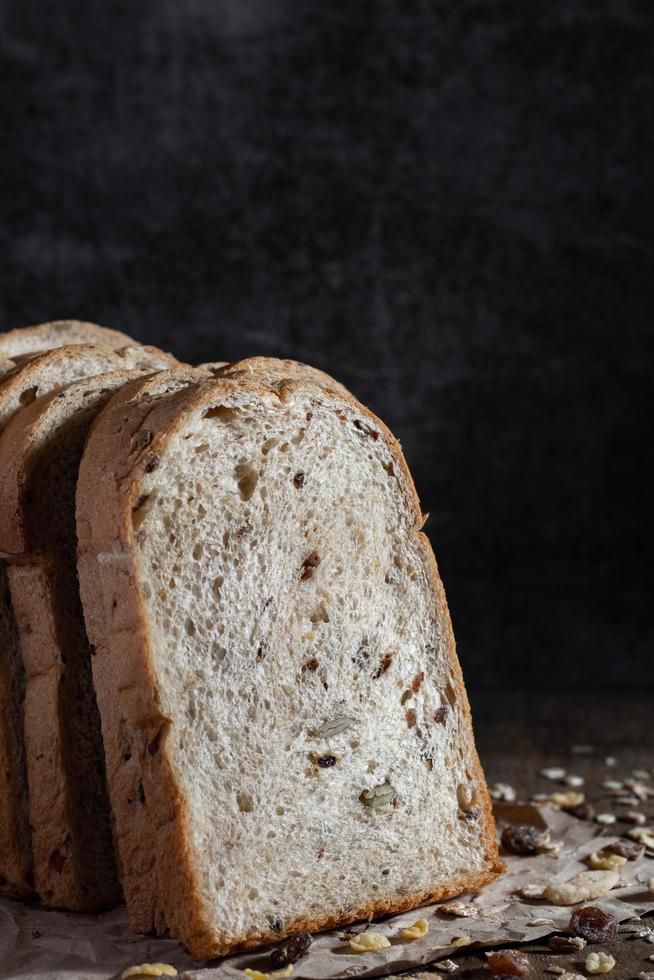 Gros plan du pain de blé entier à grains tranchés sur fond sombre photo