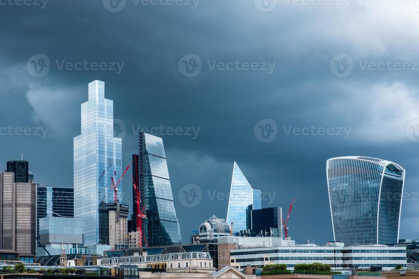 gratte-ciel brillants du quartier des affaires de la ville de londres contre le ciel orageux. photo