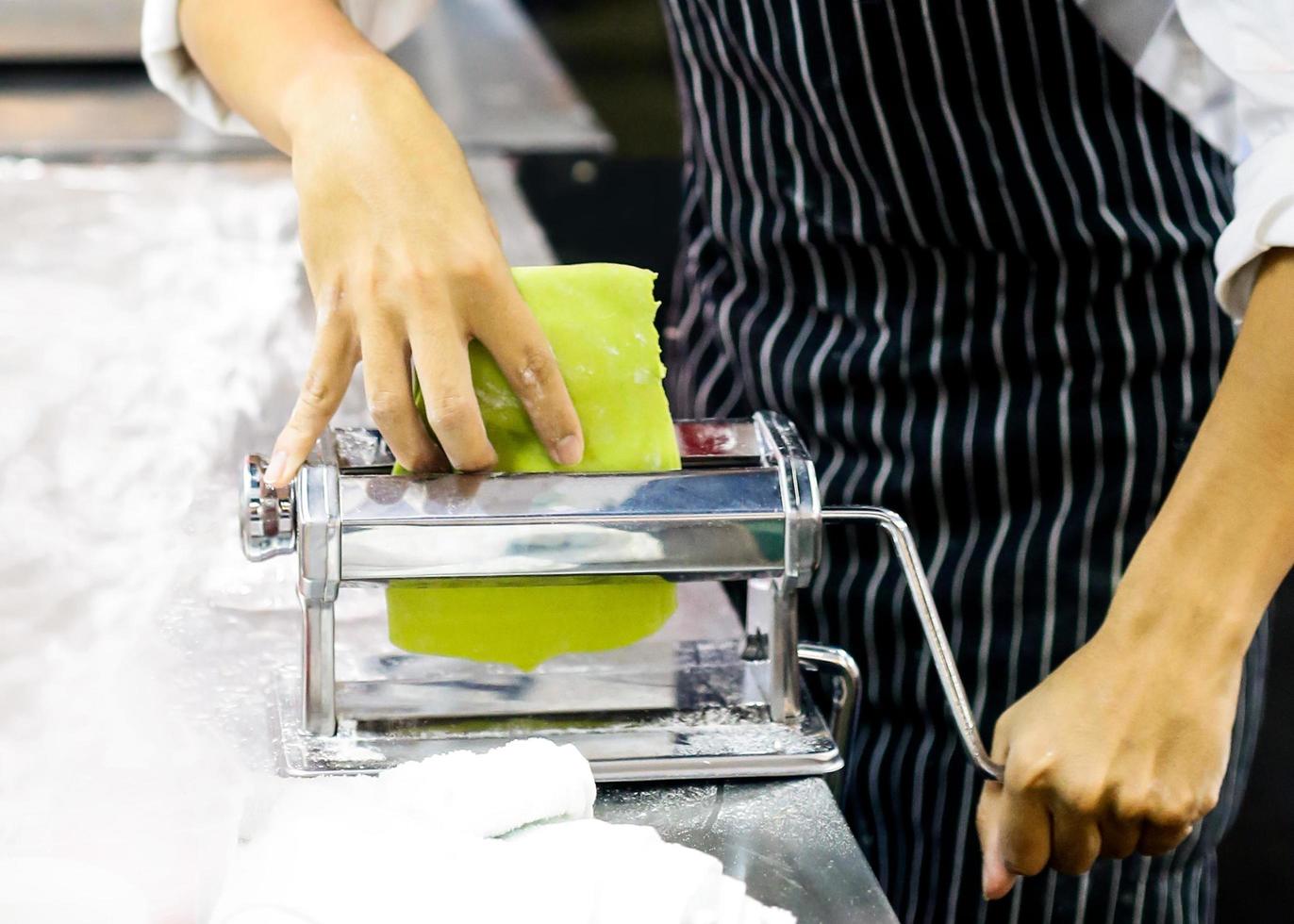 chef faisant de la pâte pour la pâtisserie, les pâtes fraîches et la machine à pâtes dans la cuisine photo