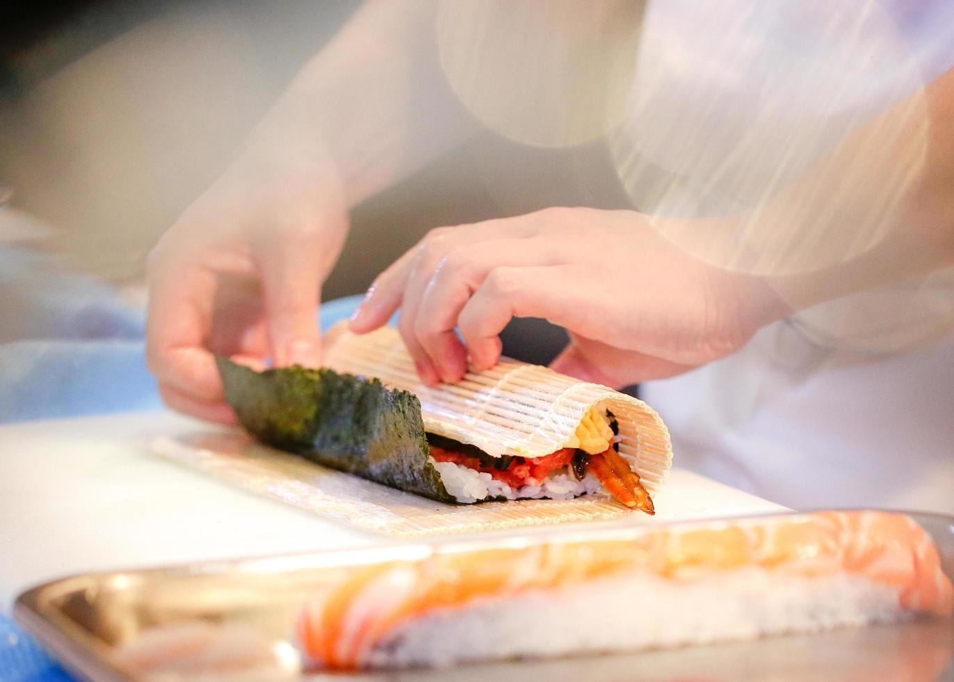 mains de chef préparant la nourriture japonaise, chef faisant des sushis photo