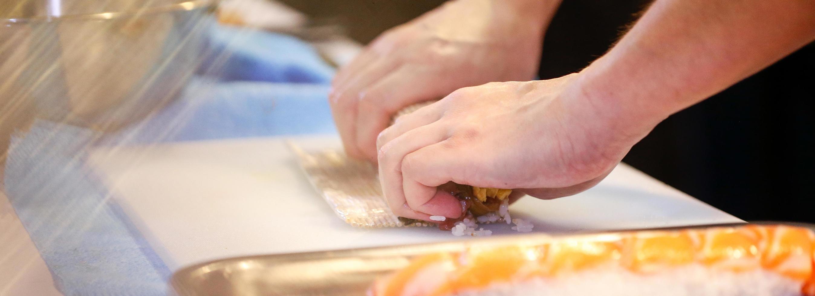 mains de chef préparant la nourriture japonaise, chef faisant des sushis photo