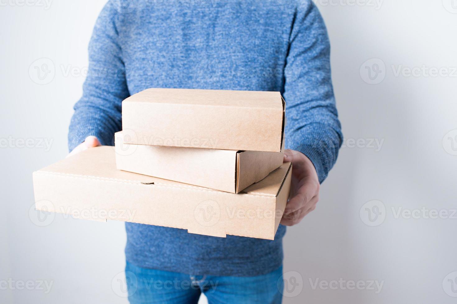 jeune homme anonyme avec des jeans livrant des boîtes en carton photo