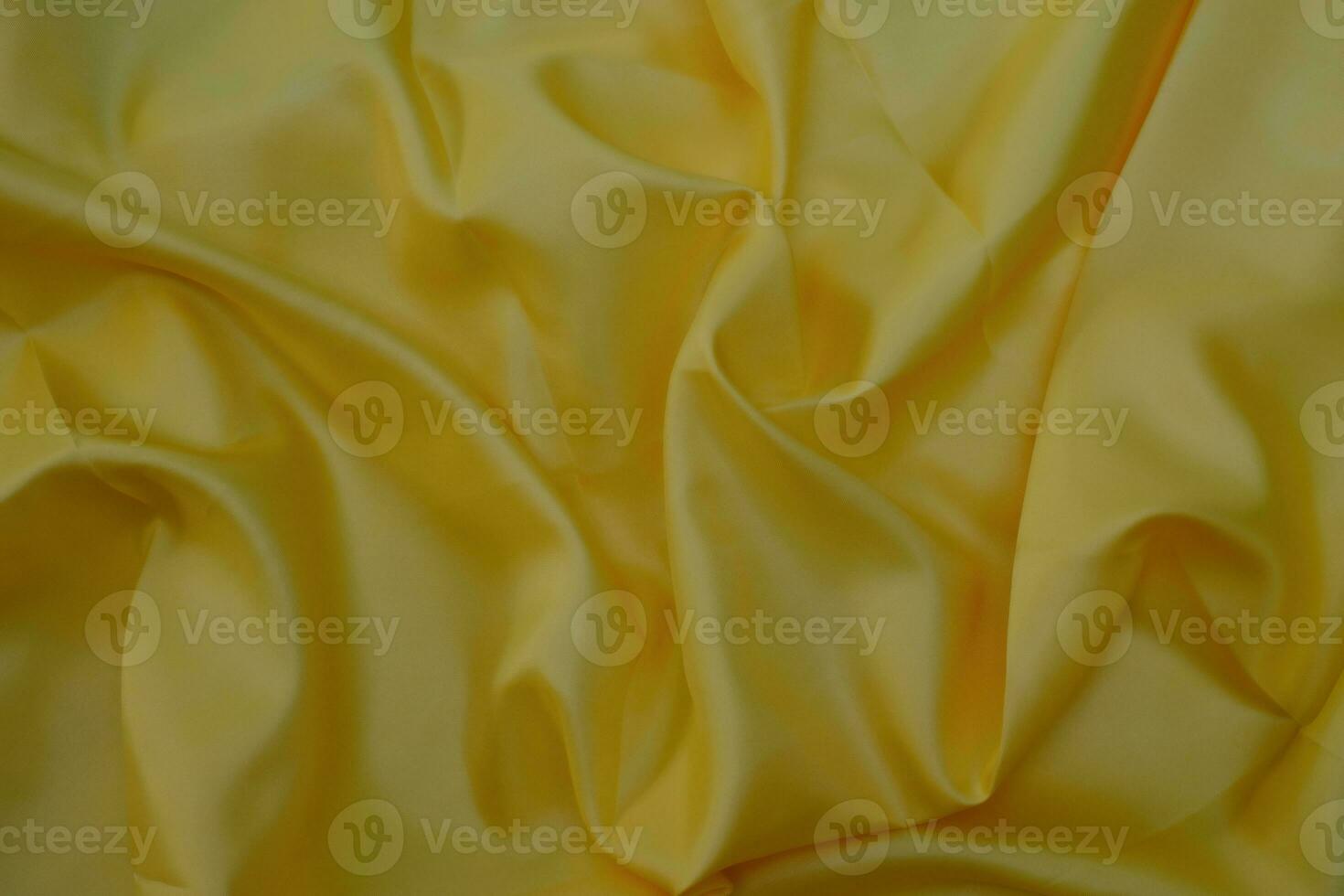 Gros plan de la texture du tissu de luxe en tissu de soie jaune élégant et lisse photo