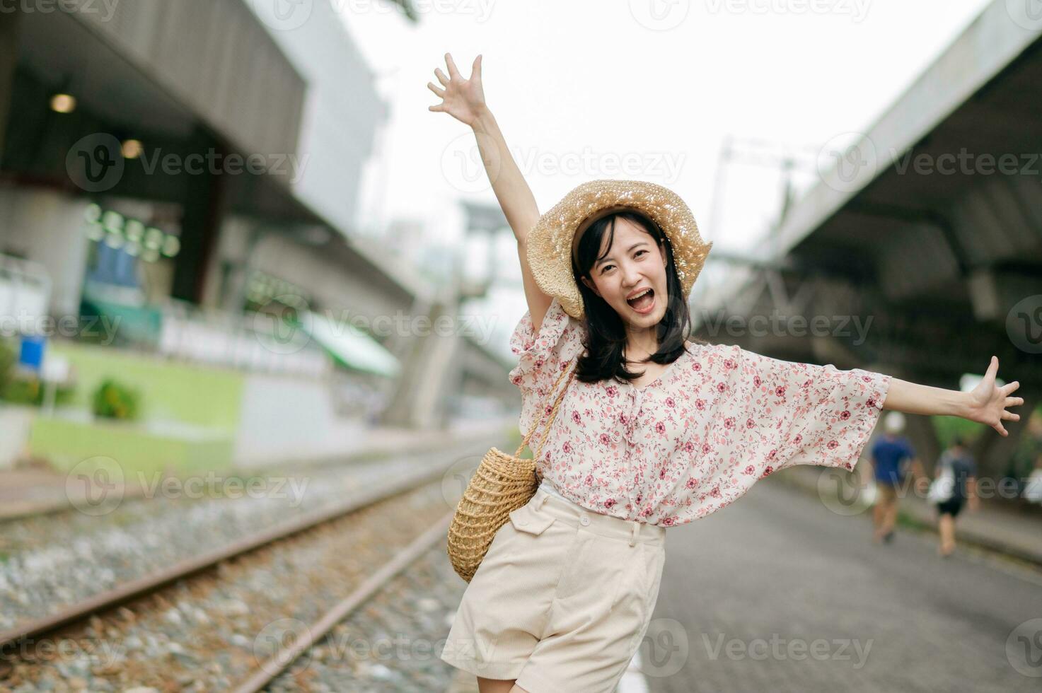 Jeune asiatique femme voyageur avec tissage panier content souriant à la recherche à une caméra à côté de train chemin de fer. périple voyage mode de vie, monde Voyage explorateur ou Asie été tourisme concept. photo