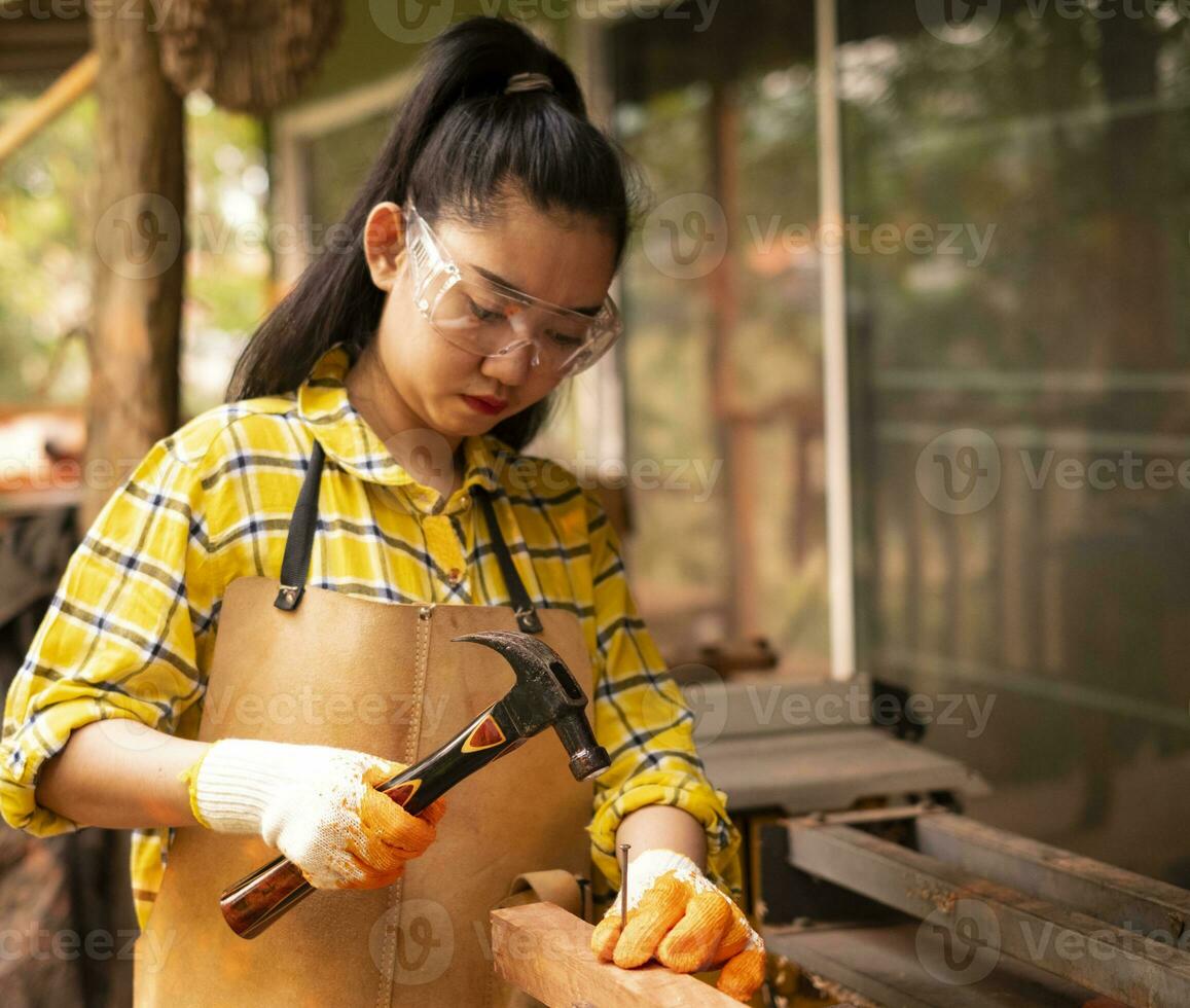 Femme debout builder worker hammering nail dans la planche de bois photo