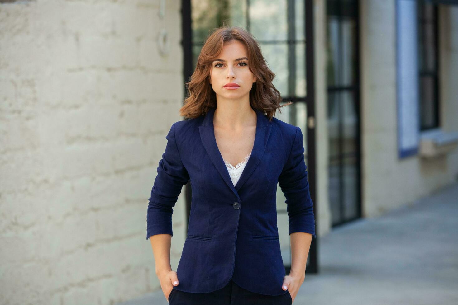 portrait de une réussi affaires femme dans de face de moderne affaires bâtiment. Jeune directeur pose dehors. femme employé de un bureau. photo