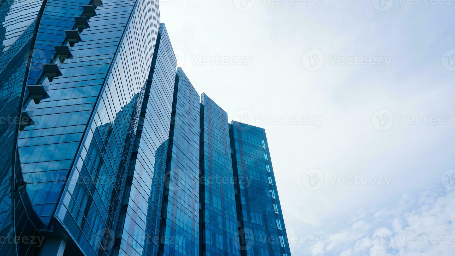 bas vue bleu des lunettes bâtiment avec ciel et nuage Contexte. gratte-ciel, vue de moderne affaires bâtiment. maquette moderne bleu des lunettes bâtiment paysage. à la recherche en haut perspective. copie espace photo