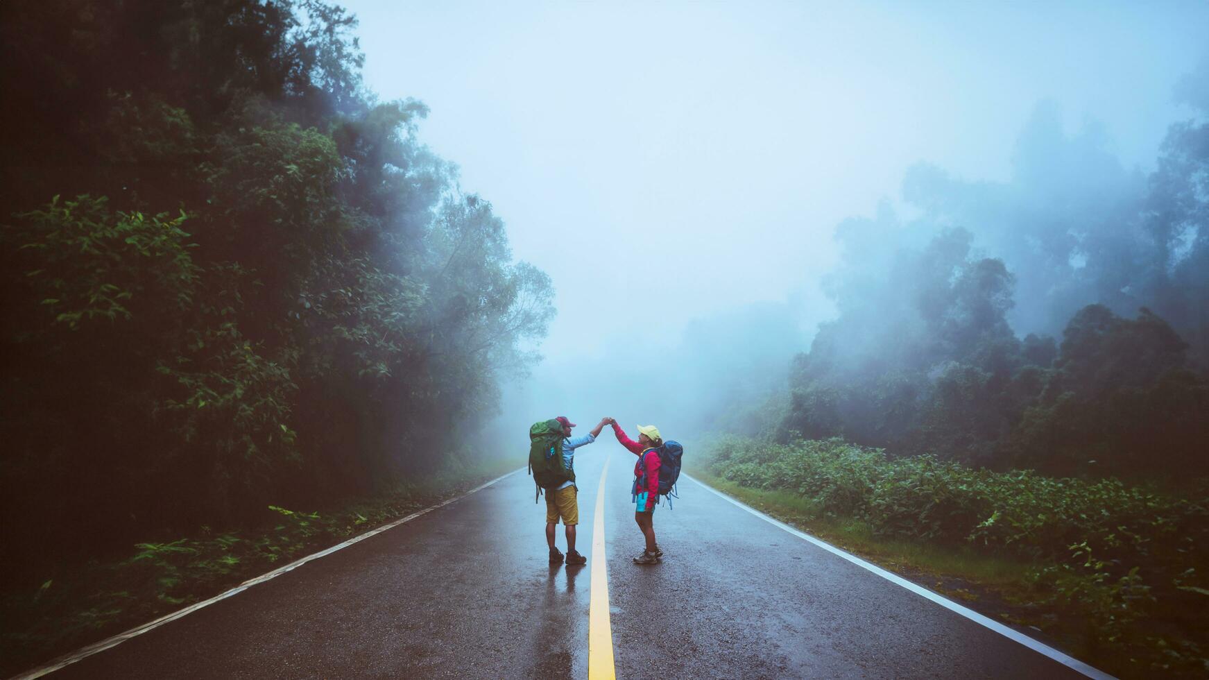 l'homme asiatique amoureux et les femmes asiatiques voyagent dans la nature. marcher sur la route. voyager dans la nature avec bonheur. au milieu de la brume pluvieuse. photo