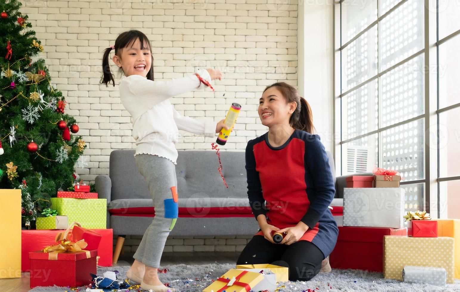 mère et fille asiatiques célèbrent noël avec des confettis à la maison photo