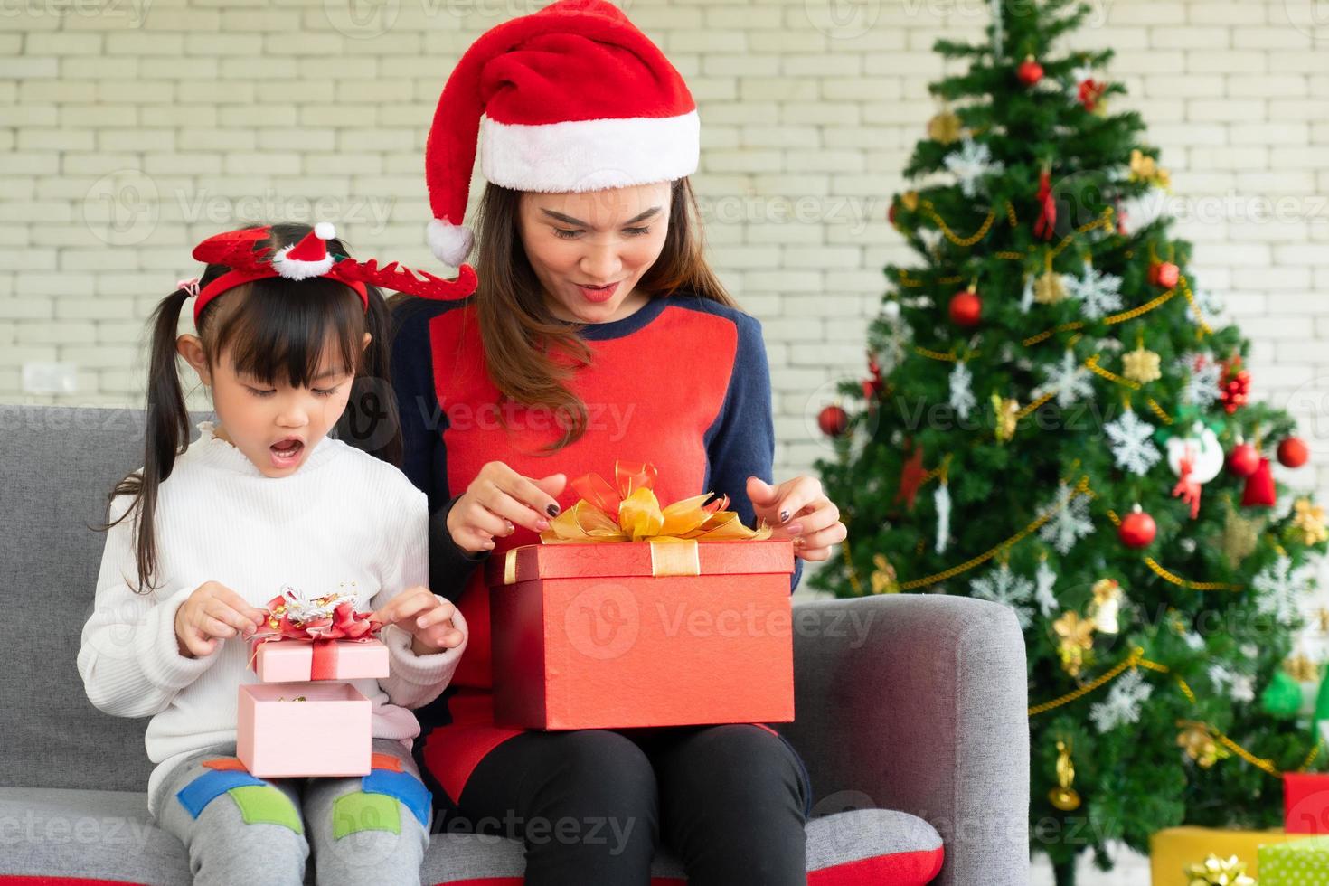 La mère et l'enfant asiatiques ouvrent la boîte de cadeau de Noël ensemble photo