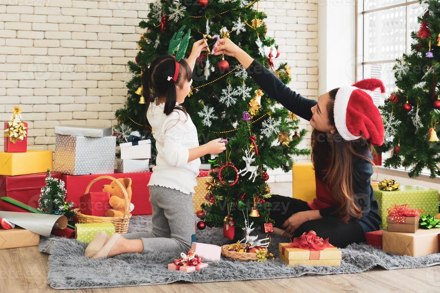 La mère et l'enfant asiatiques décorent ensemble l'arbre de Noël photo