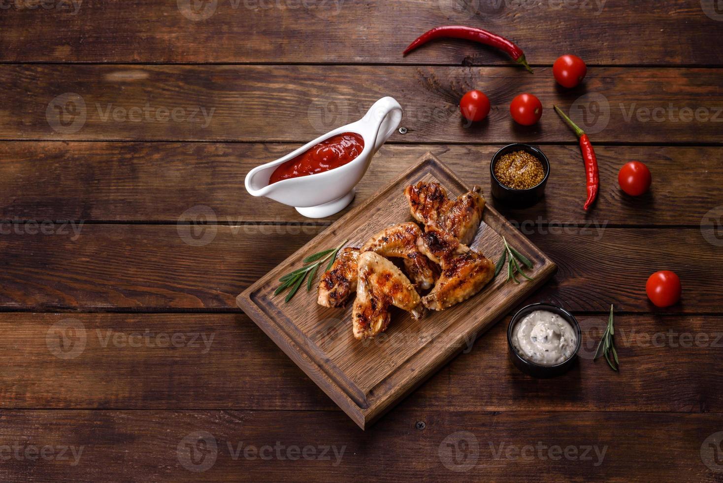 ailes de poulet épicées grillées sur fond sombre avec épices et herbes photo