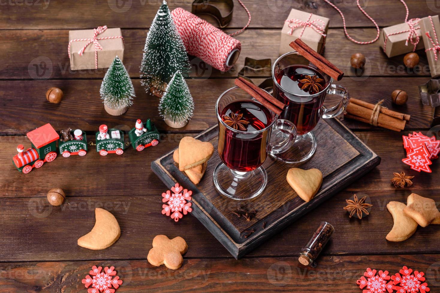 vin rouge chaud de noël avec des épices et des fruits sur une table sombre. photo