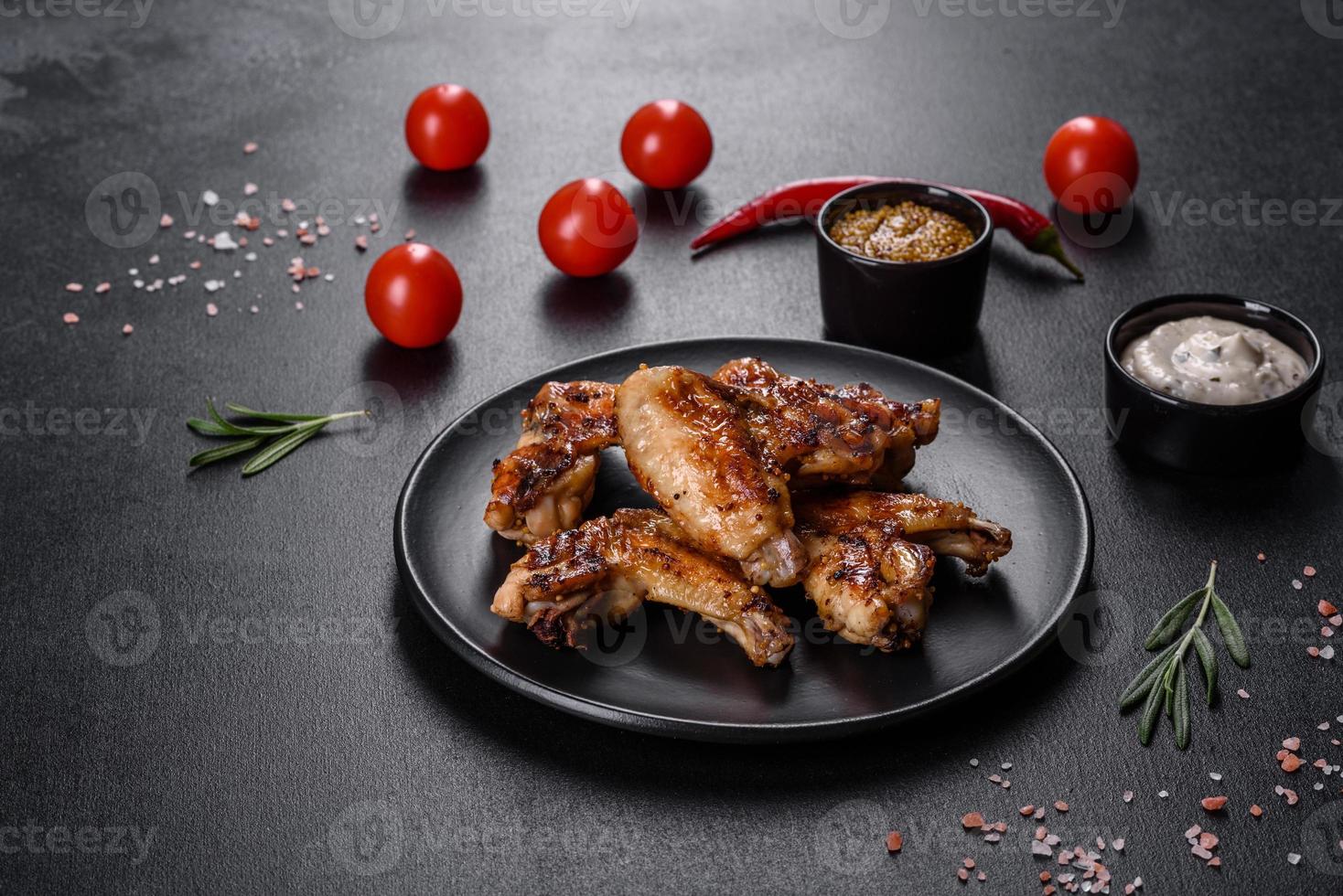 ailes de poulet épicées grillées sur fond sombre avec épices et herbes photo