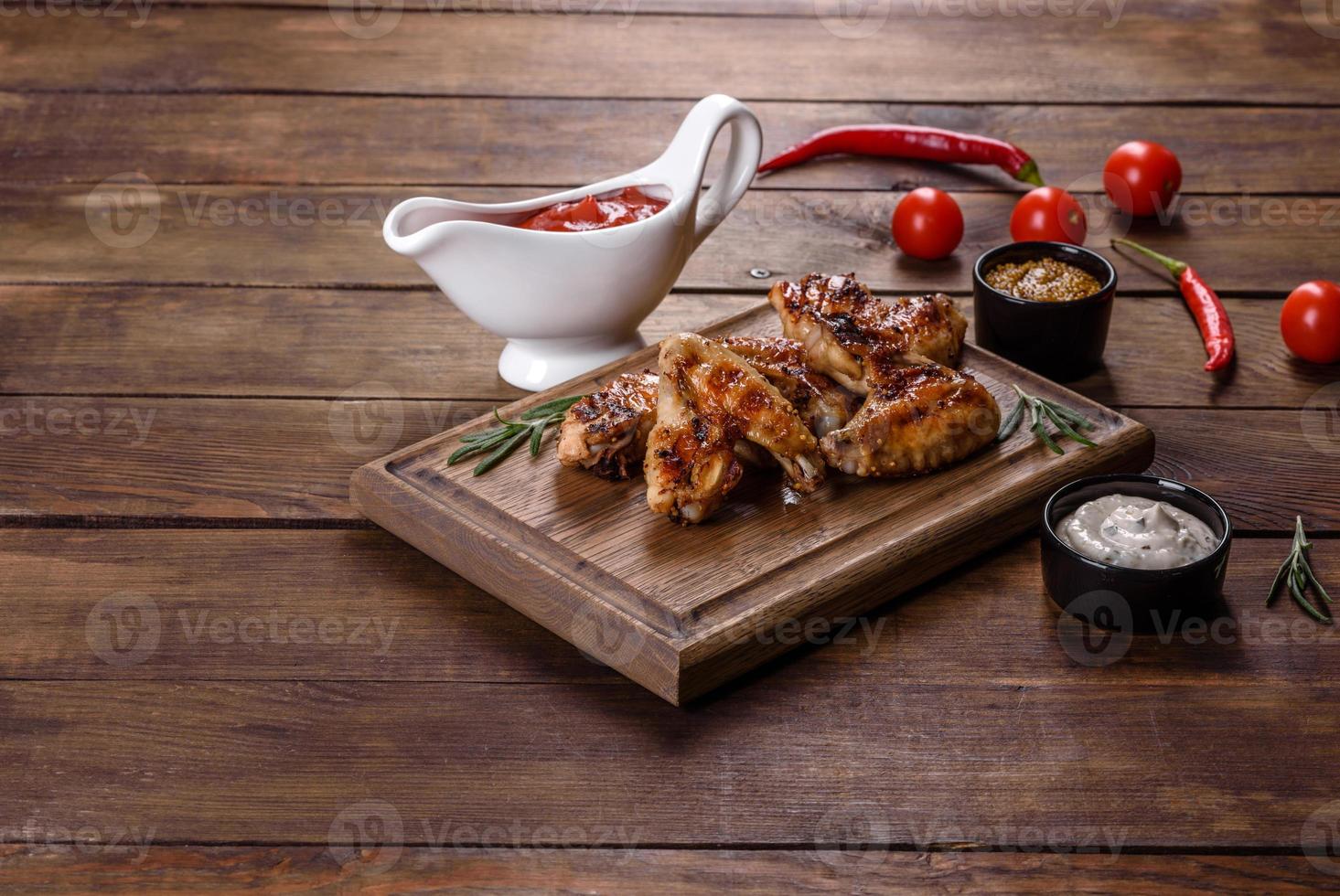 ailes de poulet épicées grillées sur fond sombre avec épices et herbes photo