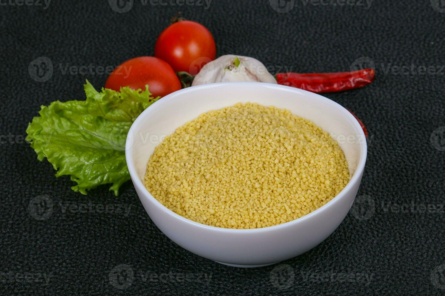 couscous cru dans le bol servi feuilles de salade, tomate et poivron photo