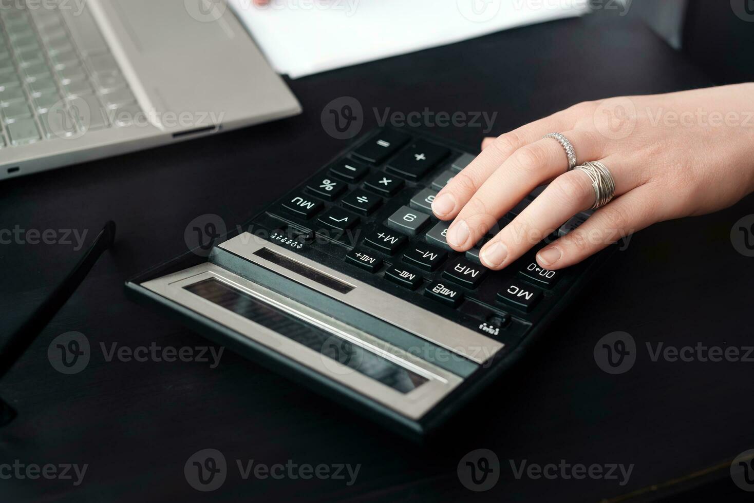 efficace financier gestion. femme comptable les usages calculatrice et ordinateur portable, tous les deux dans Bureau et tandis que travail de Accueil photo