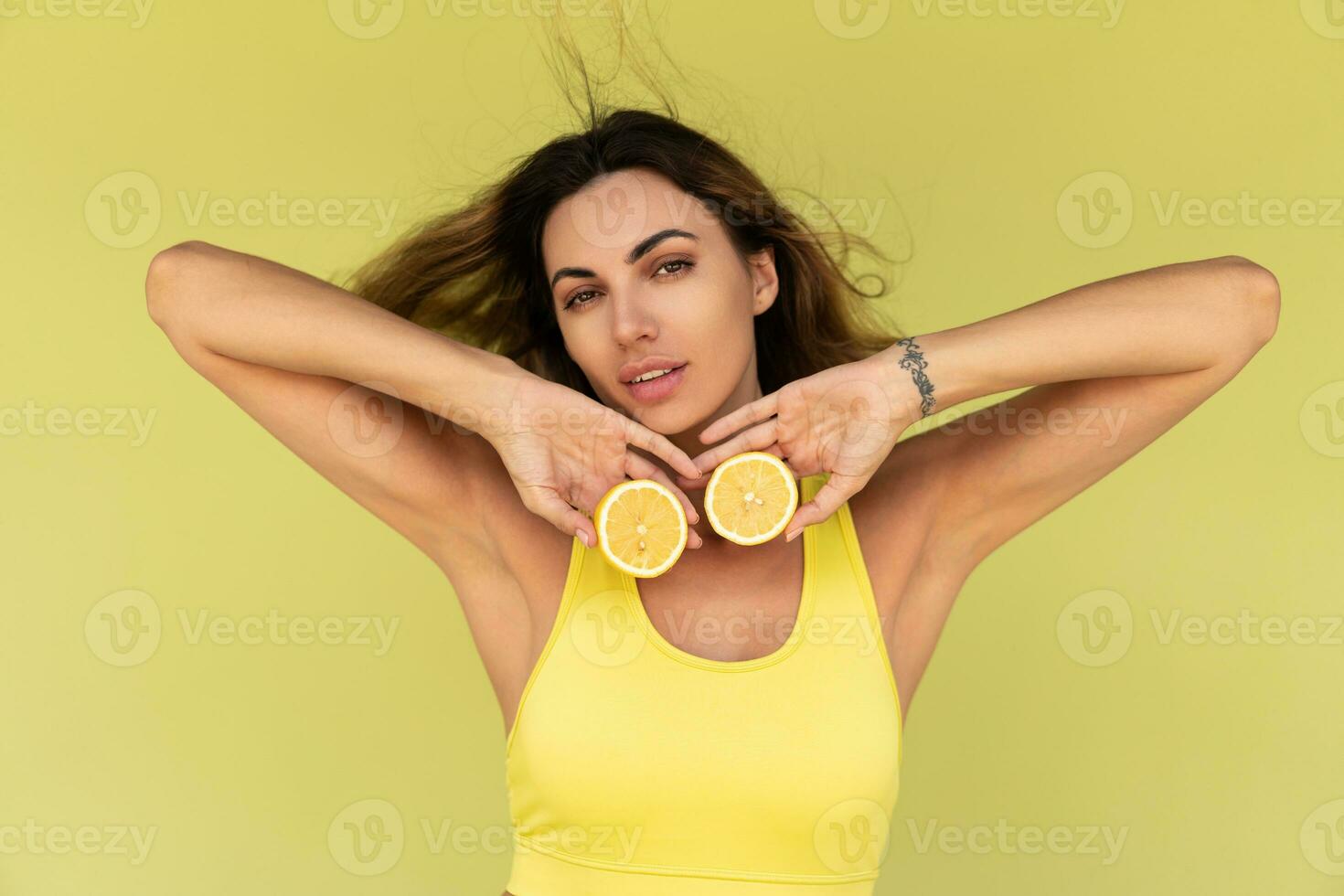 magnifique femme posant plus de vert Contexte , en portant Frais citrons. beauté studio portrait. en bonne santé la vie style. photo