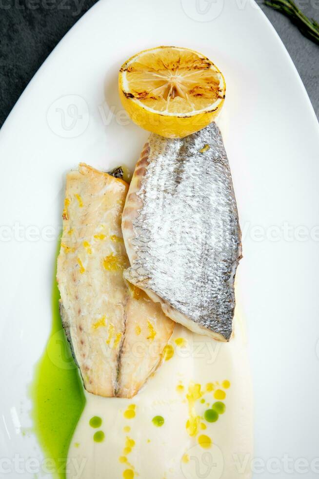 pièces de frit poisson avec sauce et frit citron sur une blanc assiette côté vue photo