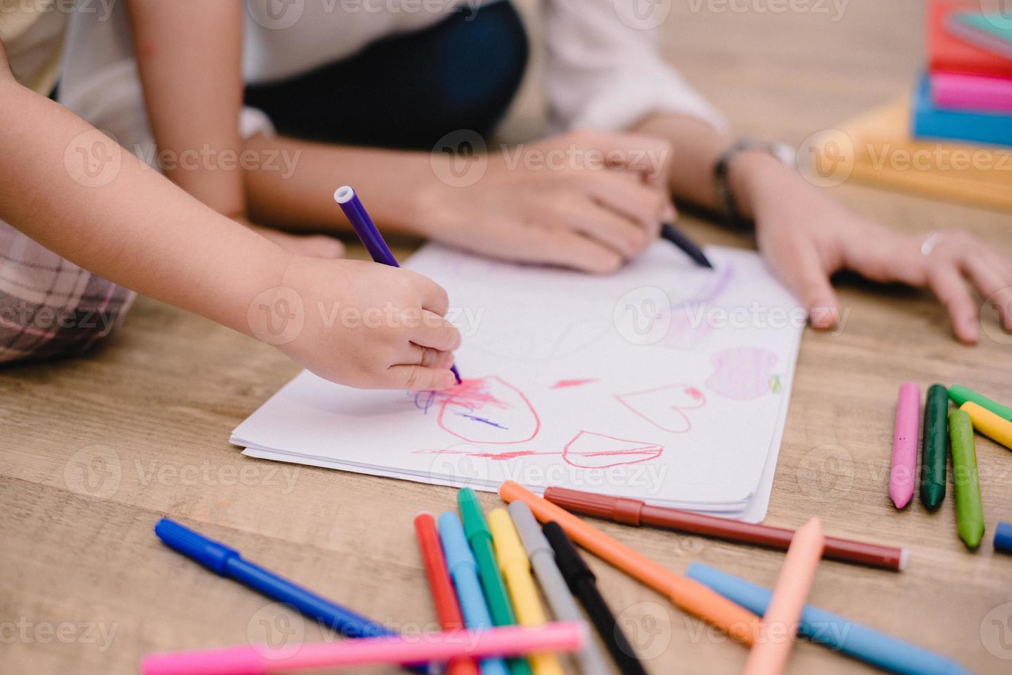 fermé les mains de maman enseignant aux petits enfants à dessiner des dessins animés photo