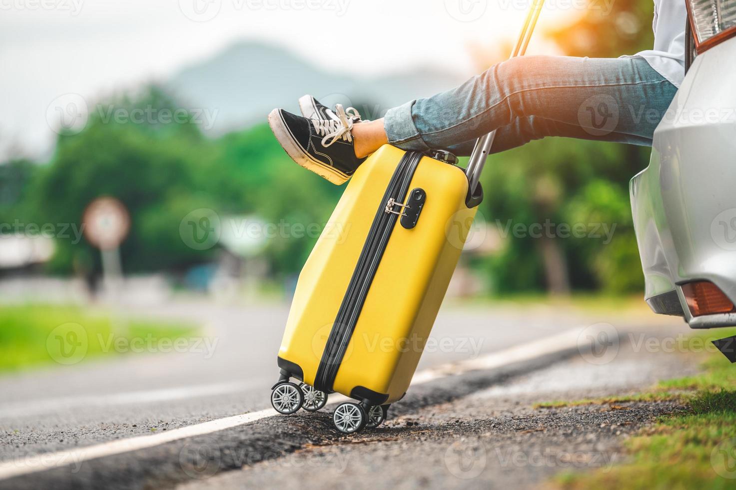 Gros plan sur des bagages jaunes et des jambes de femme se relaxant à l'arrière de la voiture photo