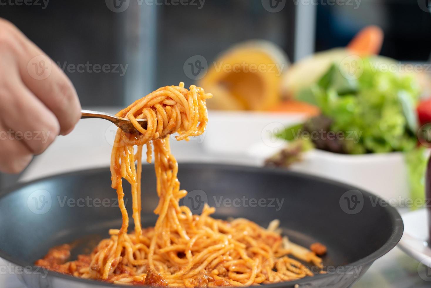 spaghetti soulevé par fourchette avec salade de légumes et plat photo