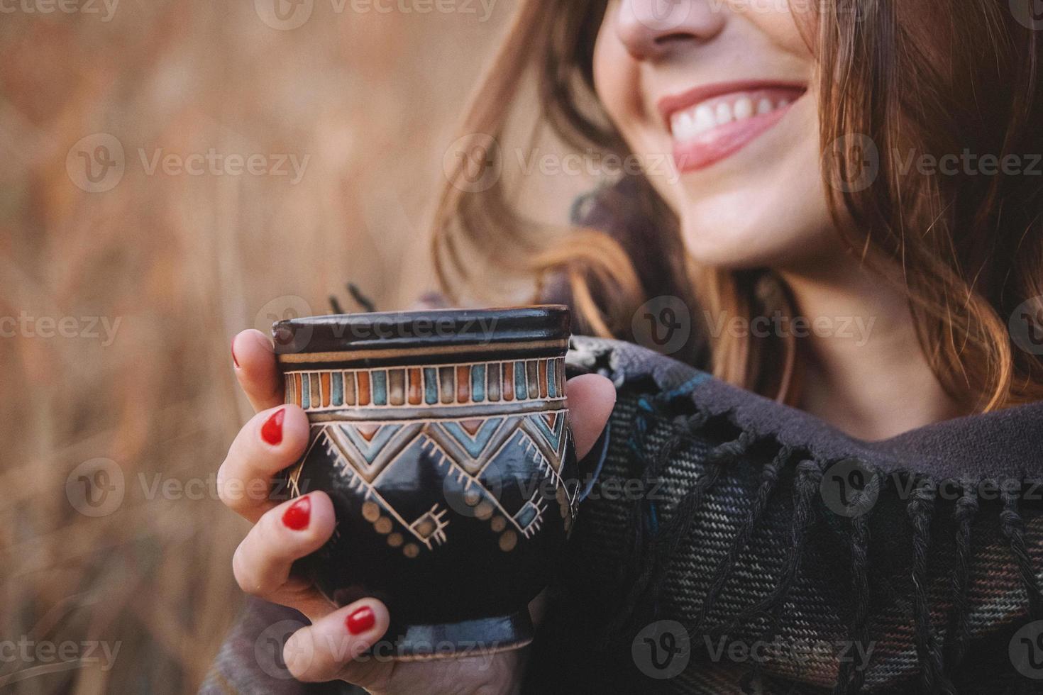 belle femme sourit et tient une tasse avec un verre photo