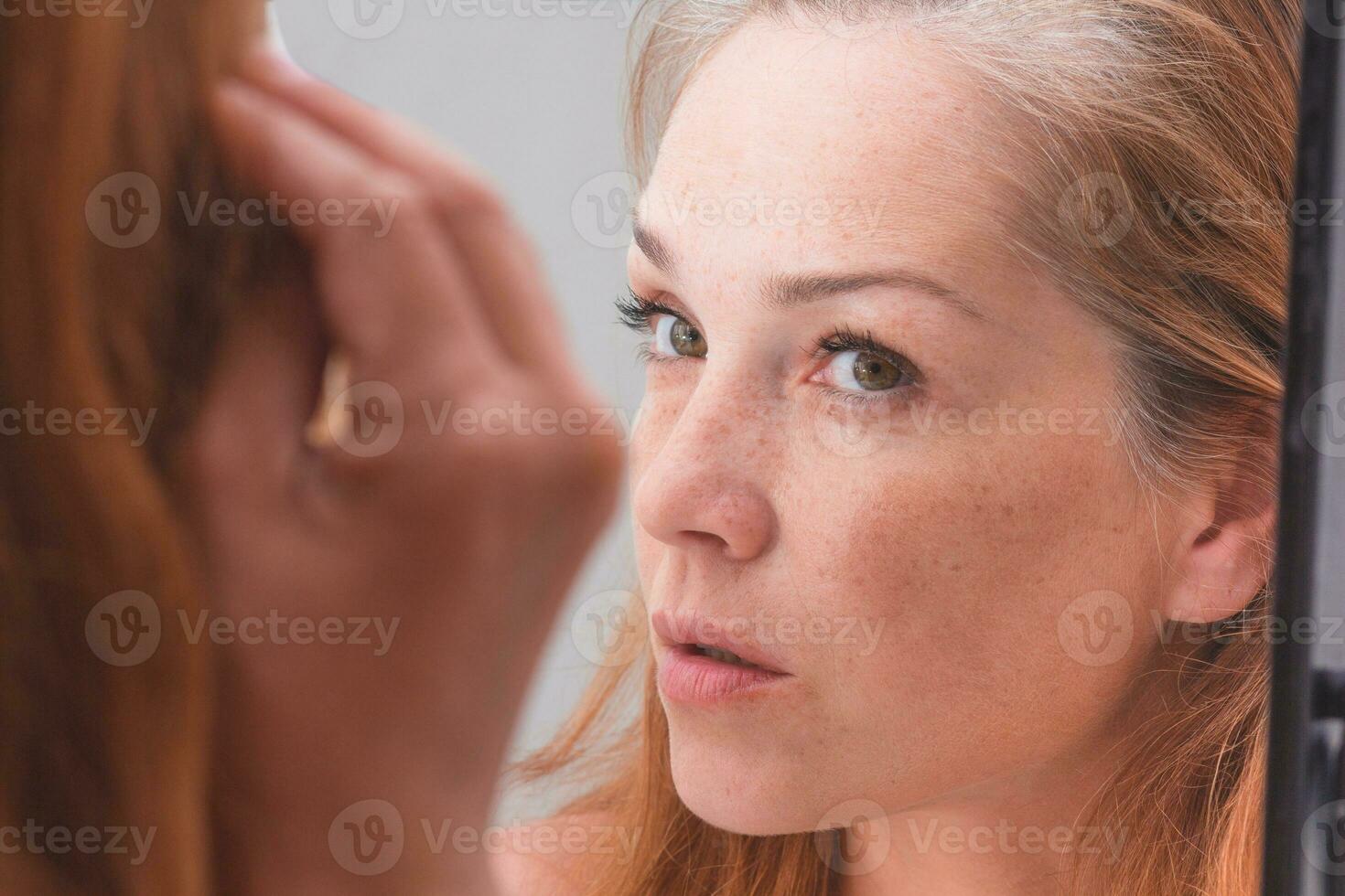 femme aux cheveux gris regardant la réflexion dans le morror photo