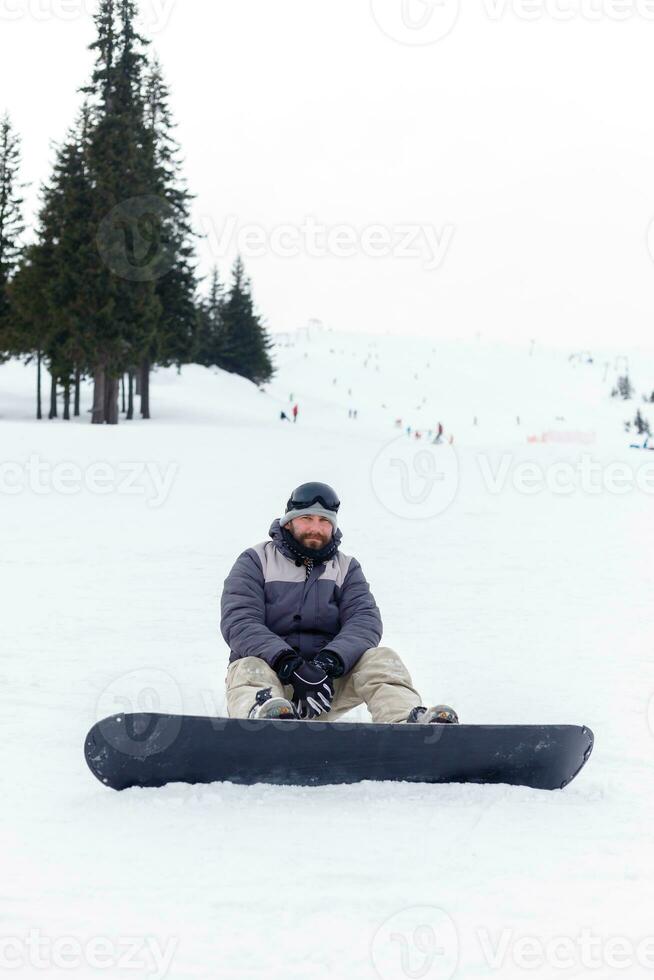 snowboarder séance à le Haut de une Montagne photo