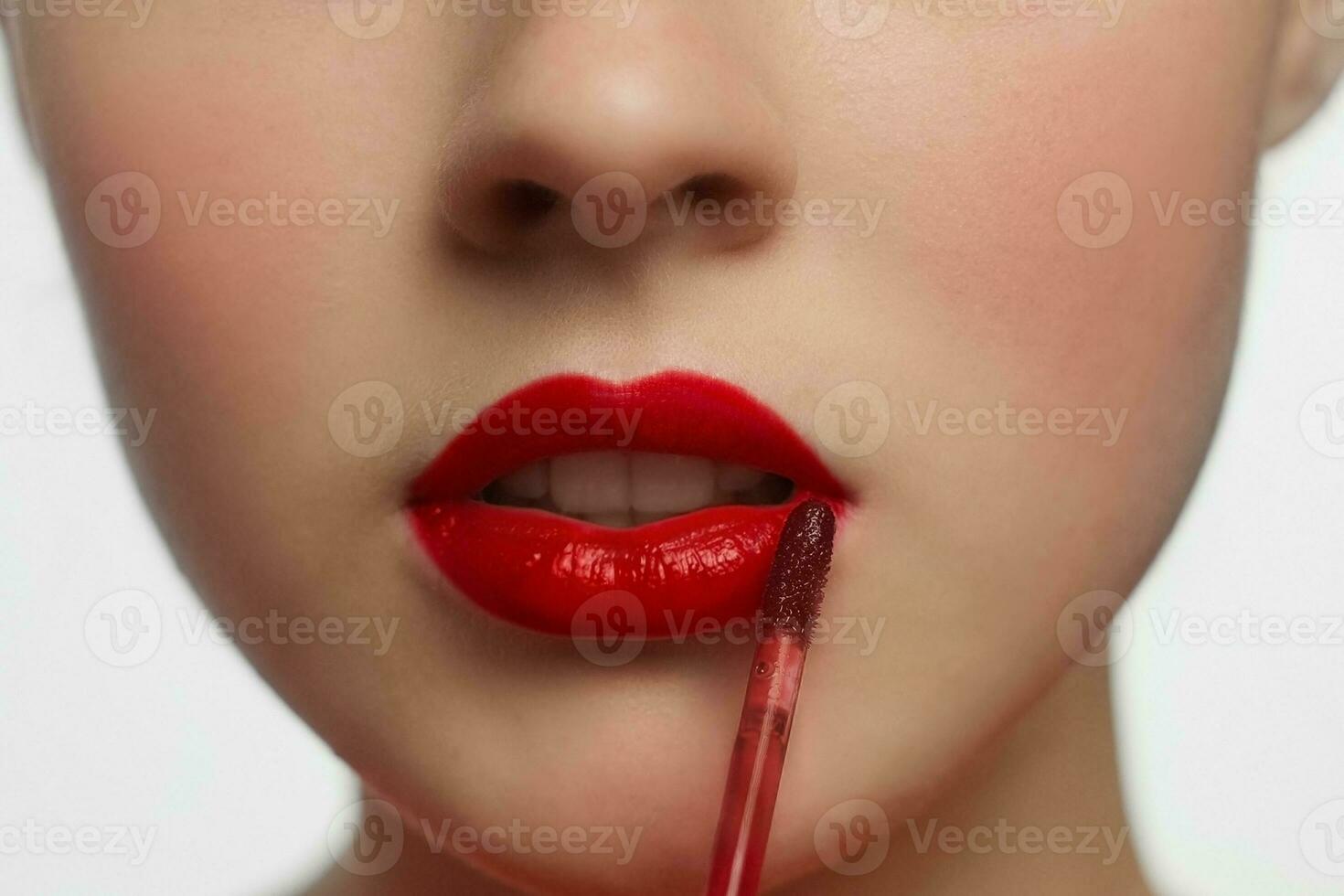 Jeune femme appliquant rouge rouge à lèvres à sa lèvres, femelle visage fermer. photo