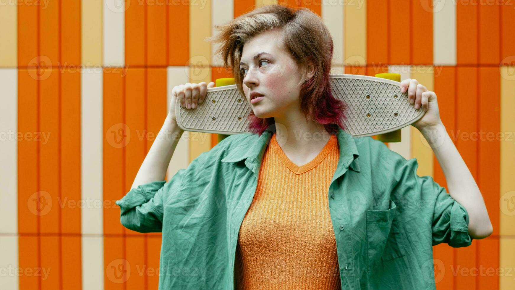 actif sportif patineur fille avec Plastique planche à roulette contre coloré Urbain mur. photo